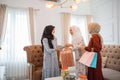 two women in veils give paper bags to host woman