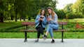 Two women violate quarantine and sitting on a bench in park and using mobile phone