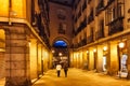Two women walk along Madrid pedestrian street at night.