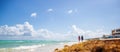 Two women walk on the beach in a summer vacation destination with blue sea next to them Royalty Free Stock Photo