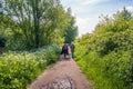 Two women walk on a narrow hiking trail in nature