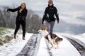 Two woman walk with their dog, tugging on the leash