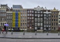 Two tourists walk under the umbrella along the canal of Amsterdam.