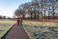 Two women walking along a path among the frozen grass