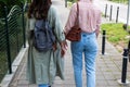 Two women walking down the street, one of her wallet falls out of her coat pocket, she doesnt notice. Lost wallet concept
