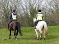 Two women, wearing high visibility jackets, riding horses on Chorleywood Common in Hertfordshire, England, UK