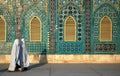 Two women wearing white burqas walk past the Blue Mosque in Mazar i Sharif, Afghanistan