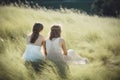 Two women in white dresses sitting in windy summer breeze on grass. Generate ai Royalty Free Stock Photo