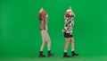 Two women in white and pink balaclavas dancing merrily. Freak women in fur coats on green studio background. Fashion