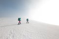 Two women on a winter hike. Girlfriends with trekking sticks go along a snow-covered mountain path. Girls with backpacks and Royalty Free Stock Photo