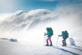 Two women on a winter hike. Girlfriends with trekking sticks go along a snow-covered mountain path. Girls with backpacks and Royalty Free Stock Photo