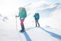 Two women on a winter hike. Girlfriends with trekking sticks go along a snow-covered mountain path. Girls with backpacks and Royalty Free Stock Photo