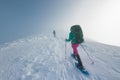 Two women on a winter hike. Girlfriends with trekking sticks go along a snow-covered mountain path. Girls with backpacks and Royalty Free Stock Photo