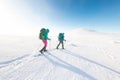 Two women on a winter hike. Girlfriends with trekking sticks go along a snow-covered mountain path. Girls with backpacks and Royalty Free Stock Photo