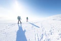 Two women on a winter hike. Girlfriends with trekking sticks go along a snow-covered mountain path. Girls with backpacks and Royalty Free Stock Photo