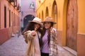 Two women, young and beautiful, with hats and coats, embraced, making the sign of thumbs up, affectionate and accomplices. Concept