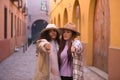 Two women, young and beautiful, wearing hats and coats, embraced, making the thumbs down sign, serious and angry. Concept beauty,