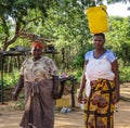 Two Women in Zimbabwe carrying Firewood and Bucket