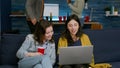 Two womens sitting on couch watching comedy series on laptop computer Royalty Free Stock Photo