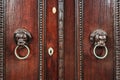 Two wood carved lion heads with metal ring as door knocker Royalty Free Stock Photo