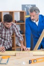 Two wood workers in carpentry measuring boards