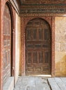 Two wooden aged ornate vaulted perpendicular doors on stone bricks walls