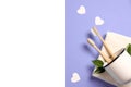 Two wooden bamboo eco friendly toothbrushes in metal cup, green leaf, white heart and towel on purple background. Royalty Free Stock Photo