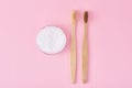 Two wooden bamboo toothbrushes and baking soda powder in glass jar on a pink background.  Teeth health and keep mouth concept Royalty Free Stock Photo