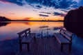 Two wooden bench or chairs on a wood dock facing a lake at sunset in Finland Royalty Free Stock Photo