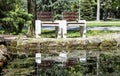 Two wooden benches reflecting in water in the park