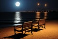 two wooden benches sitting on the beach at night