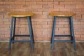 Two wooden chairs on brick wall