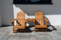 Two wooden chairs connected by a small table standing in front of a house. Royalty Free Stock Photo