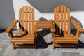 Two wooden chairs connected by a small table standing in front of a house. Royalty Free Stock Photo