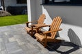 Two wooden chairs connected by a small table standing in front of a house. Royalty Free Stock Photo