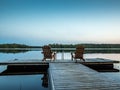 Two wooden chairs at Sunset on a pier on the shores of the calm Saimaa lakein Finland - 1