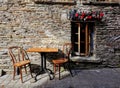 Two wooden chairs and table by a stone-built wall