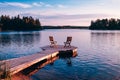 Two wooden chairs on a wood pier overlooking a lake at sunset Royalty Free Stock Photo