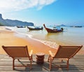 Two wooden chaise lounges and native boats