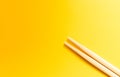 Two wooden chopsticks on a plain yellow background Royalty Free Stock Photo