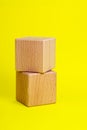 Two wooden cube square on yellow background copyspace