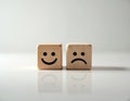 Two wooden cubes with different faces are placed on a white surface. One cube shows a happy face, while the other displays a sad Royalty Free Stock Photo