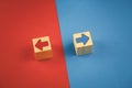 two wooden cubes with red and blue arrows on a red and blue background look in different directions Royalty Free Stock Photo