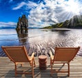 Two wooden deck chairs are on the beach