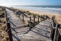 Two wooden decking pathways forming a fork in the road both heading down to a sandy beach Royalty Free Stock Photo
