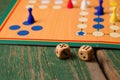 Two wooden dices in front of ludo with figurines