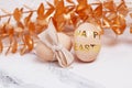 Two wooden eggs decorated with gold stickers and a ribbon bow. Royalty Free Stock Photo