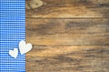 Two wooden hearts on blue checkered fabric.