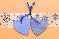 Two wooden hearts placed nicely on  pastel orange  background , snowflakes pattern,  flat lay, copy space Royalty Free Stock Photo