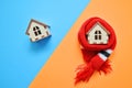 Two wooden house on blue and orange color, one house weared on scarf, concept for insulation houses, cold and warm house Royalty Free Stock Photo